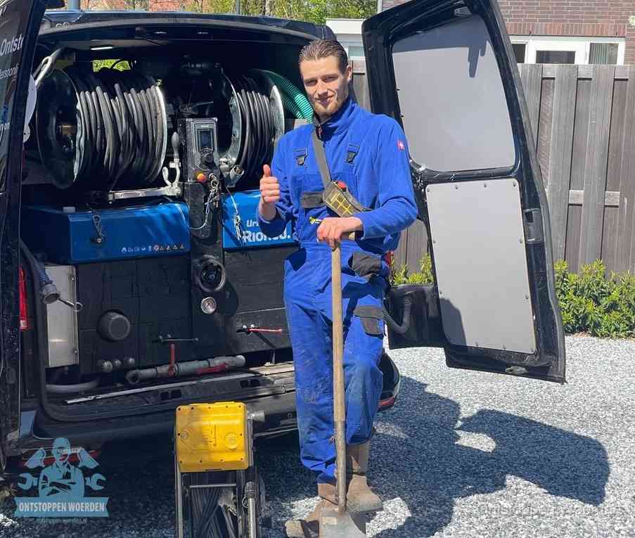 Een monteur bij de werkbus met grote hogedruk-slanghaspels, apparatuur voor hardnekkige afvoerverstoppingen in Woerden