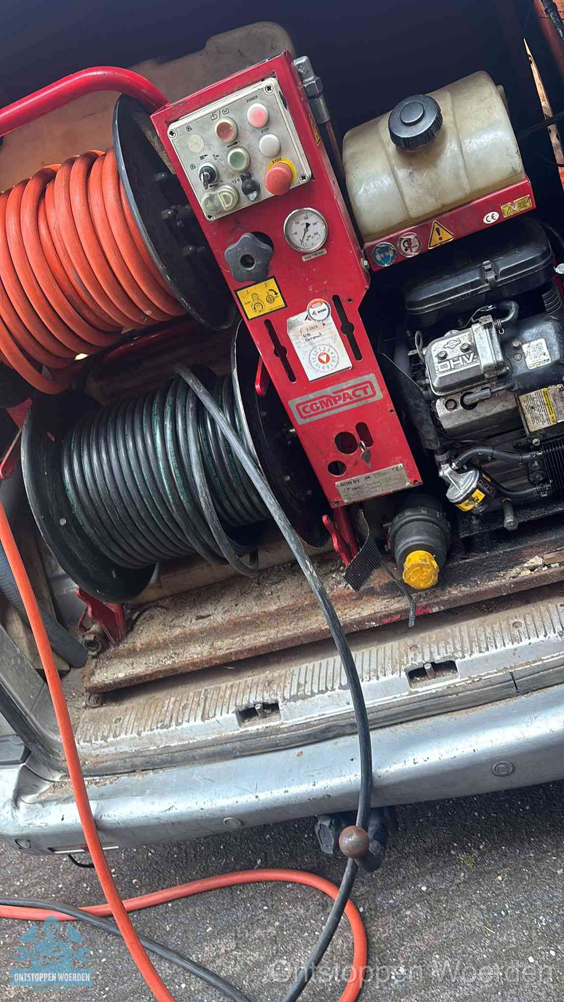 Een rood hogedruk-rioolreinigingstoestel met slangen in de laadbak van de bedrijfsbus, apparatuur voor een hardnekkige wc-verstopping in Woerden