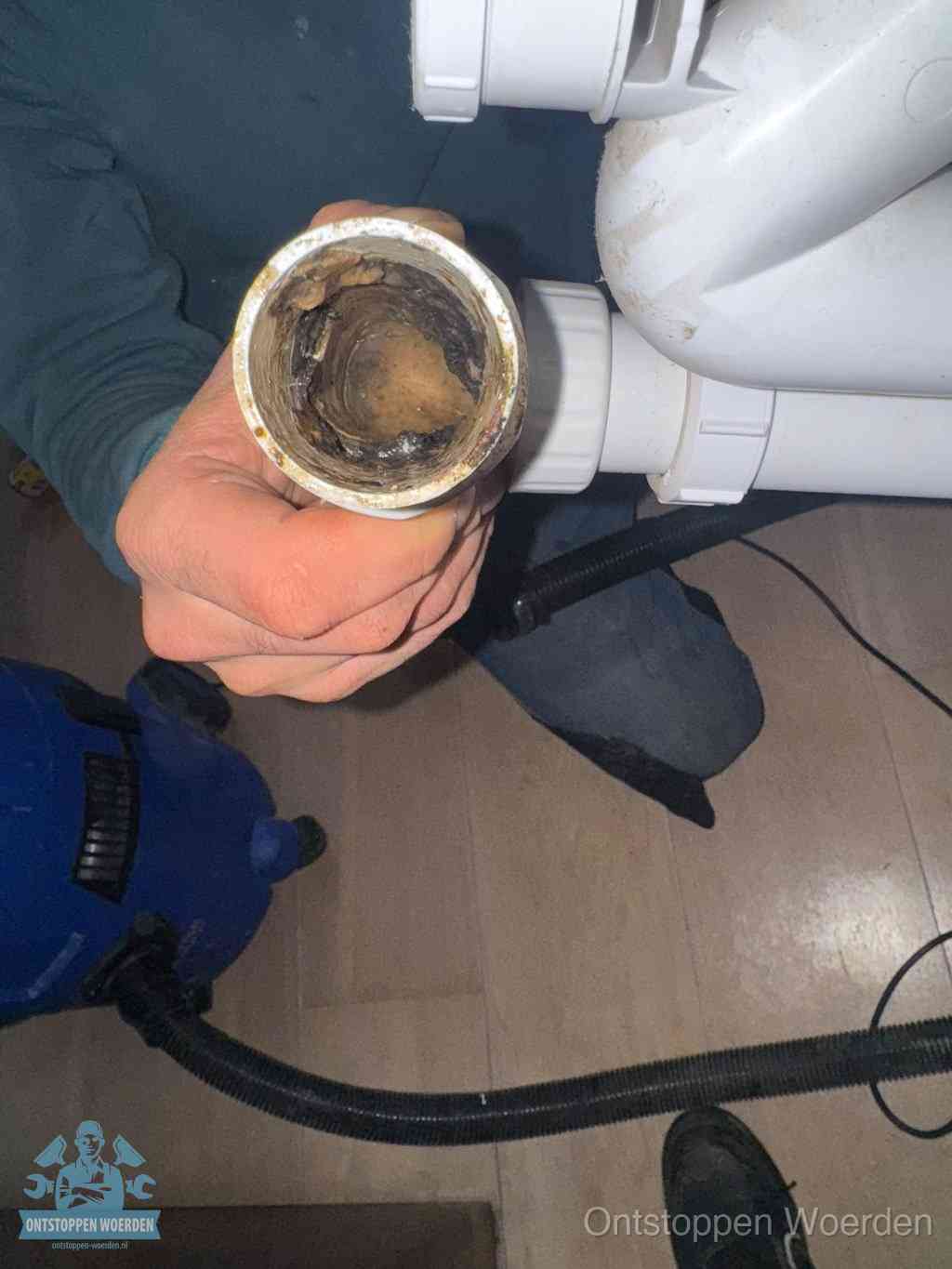 Een losgekoppelde afvoerbuis die van binnen volledig is dichtgeslibd met vet en aanslag, de meest voorkomende oorzaak van een verstopte gootsteen in Woerden