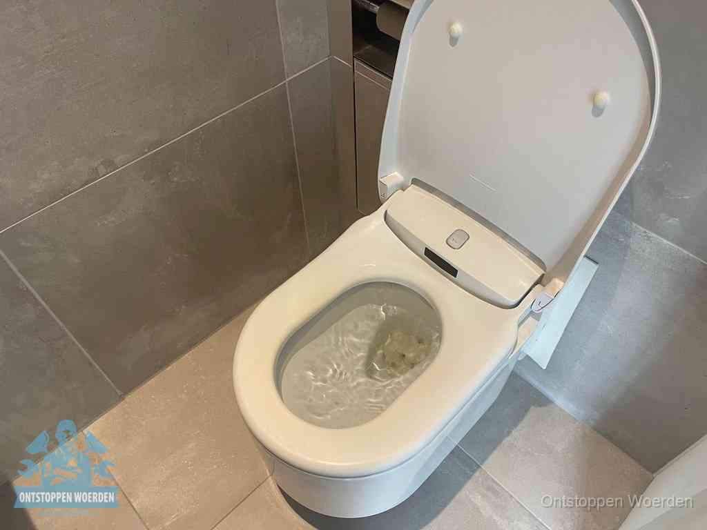 Een toiletpot vol troebel water met drijvend papier en restanten, de meest voorkomende oorzaak van een verstopte wc in Woerden