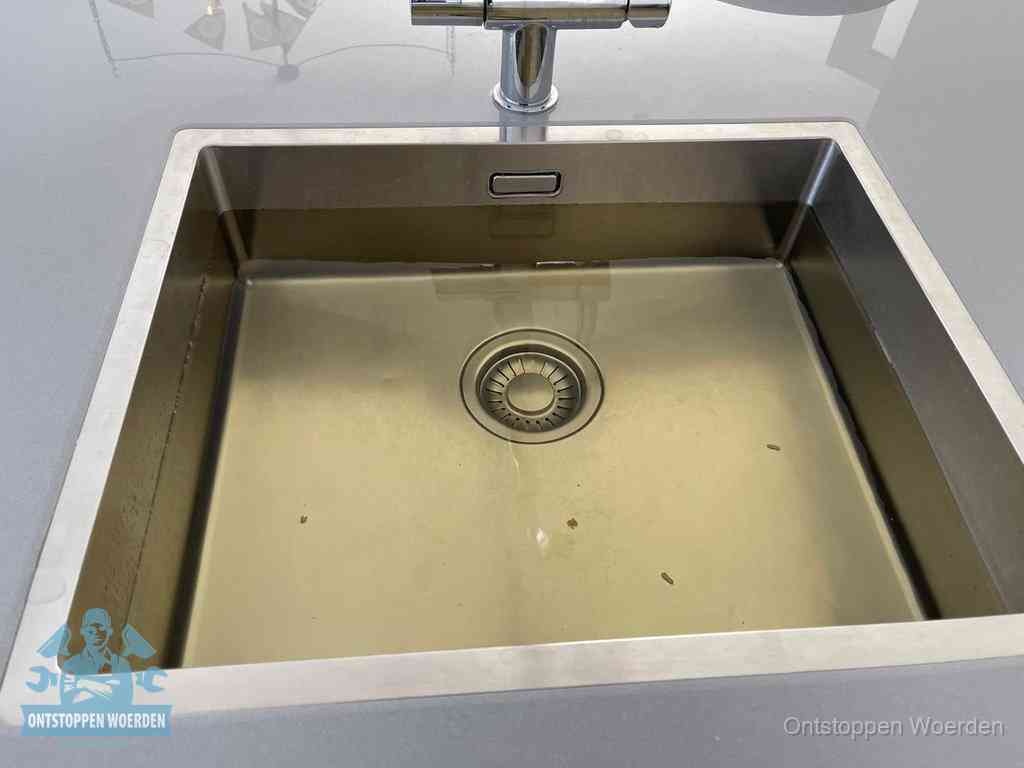 Stilstaand water in een rvs spoelbak dat niet wegloopt, een duidelijk signaal van een gootsteenverstopping in Woerden