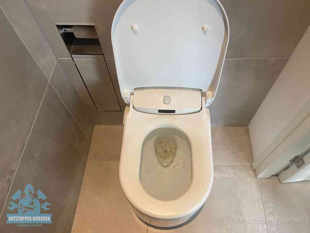 Een wit hangtoilet waarin een prop wc-papier op het water blijft drijven, een duidelijk signaal van een verstopte wc in Woerden