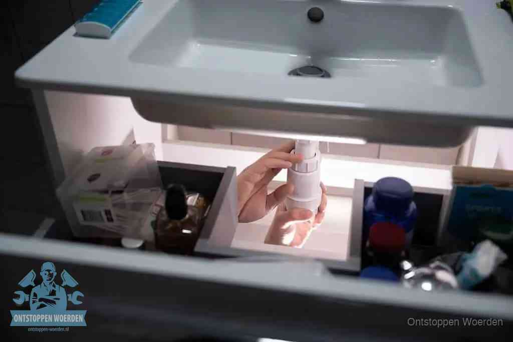 Een pompfles met zeep boven een wastafel in de toiletruimte, de warm water en afwasmiddel-methode om de wc te ontstoppen in Woerden