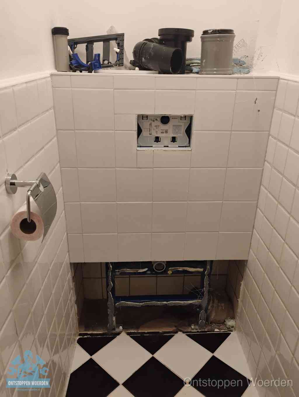 Een toiletruimte waar het hangtoilet en de inbouwreservoir-onderdelen zijn vrijgelegd voor onderhoud, periodiek nazicht voorkomt een wc-verstopping in Woerden