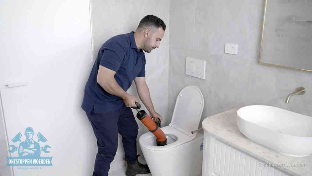 Een monteur gebruikt een handmatige perspomp (toiletontstopper) op een wandcloset tijdens het professioneel wc ontstoppen in Woerden